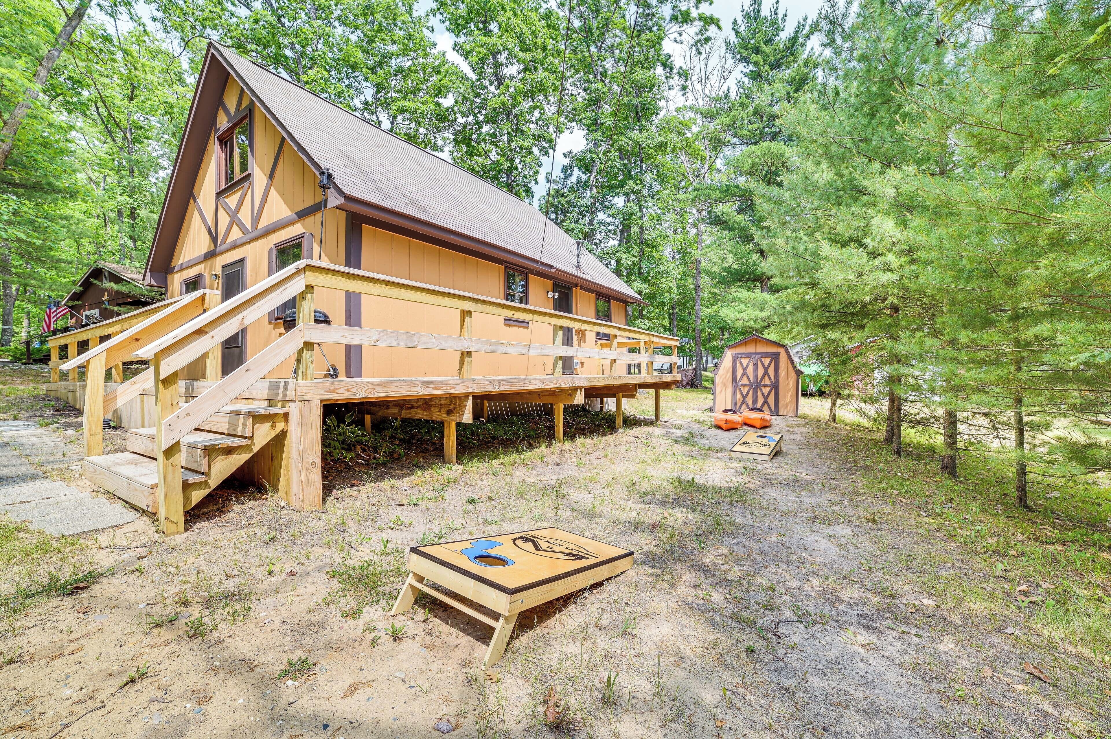 Eine Holzhütte mit einer Holzterrasse, einer kleinen Veranda und einer Haustür.