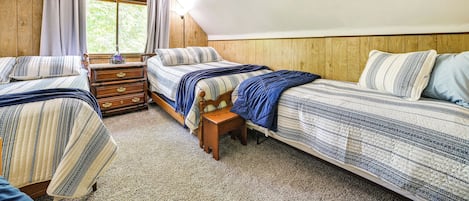Un dormitorio con dos camas, un aparador de madera y un ventanal con cortinas.