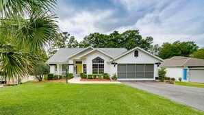 A single-story house with a garage, a front lawn, and a palm tree.