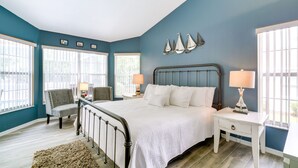 A bedroom with a bed, two nightstands, a chair, and a ceiling fan.