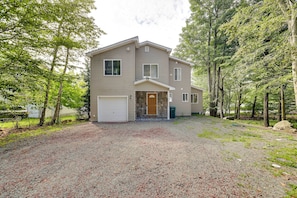 A two-story house with a front garage, surrounded by trees.