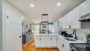A modern kitchen with white cabinetry, a central island, and a stove. - Community Perks: Family Poconos Home w/ Deck! (Tobyhanna)