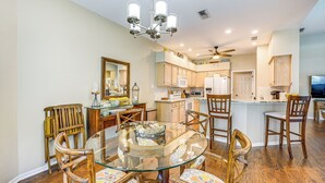 A modern kitchen with wooden cabinets, a glass dining table, and a chandelier. - Private Outdoor Pool in Naples Vacation Rental! (Naples)