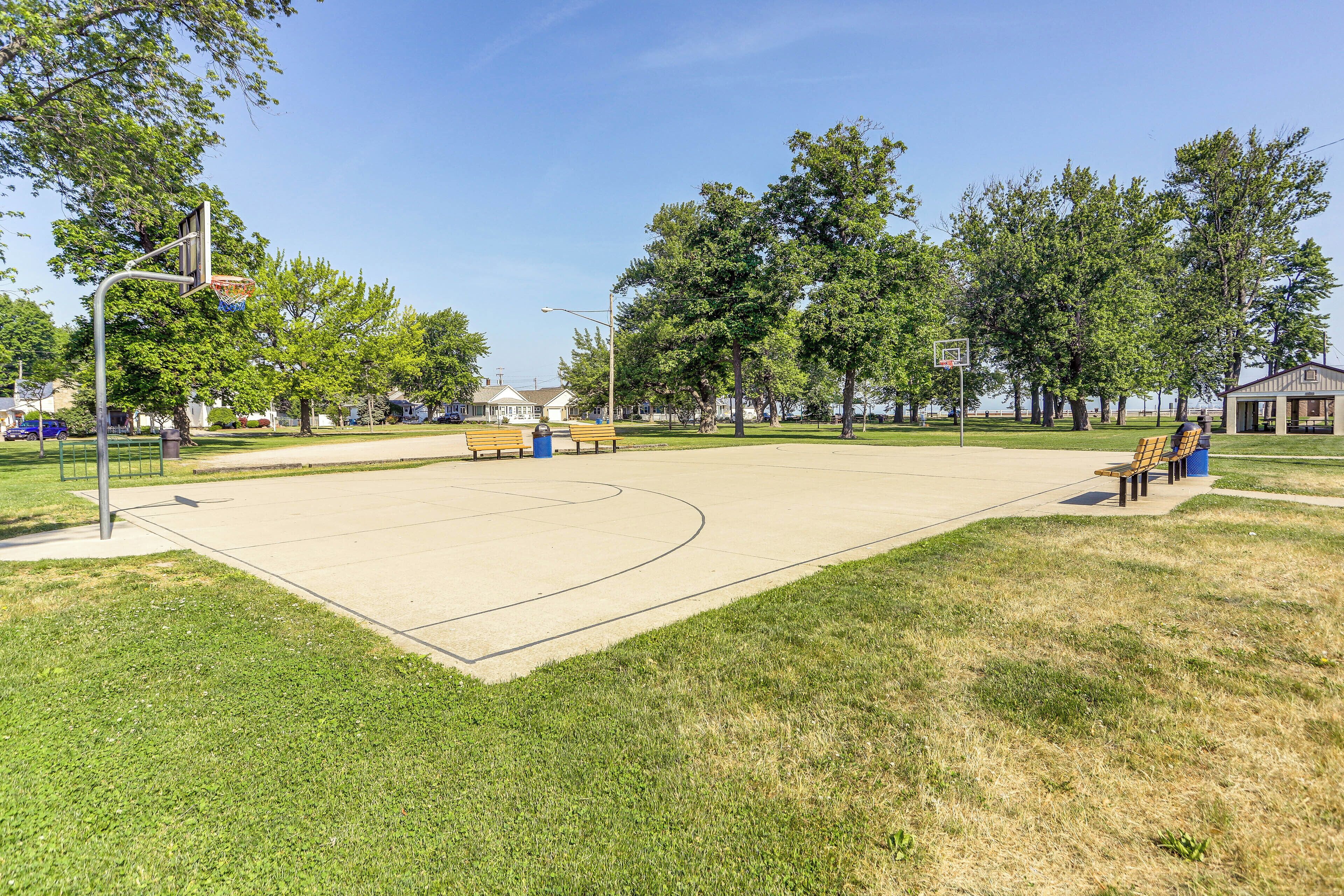 Un campo da basket con panchine e alberi.