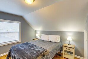 A bedroom with a bed, two bedside tables with lamps, a window with blinds, and a sloped ceiling. - Dog-friendly Port Clinton Home: Walk to Lake Erie! (Port Clinton)