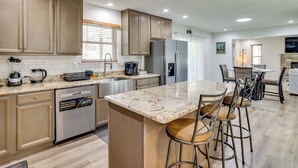 A modern kitchen with a central island, stainless steel appliances, and bar stools. - Hot Tub + Lake Access: Spacious Tobyhanna Home (Tobyhanna)