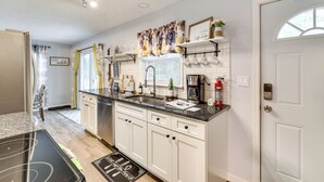 A modern kitchen with white cabinets, a granite countertop, and a built-in dishwasher. - 5 Mi to Tobyhanna State Park: Home w/ Game Room! (Tobyhanna)