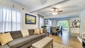 A living room with a grey sectional sofa, a matching ottoman, a ceiling fan, and a dining area with a table and chairs. - 5 Mi to Tobyhanna State Park: Home w/ Game Room! (Tobyhanna)
