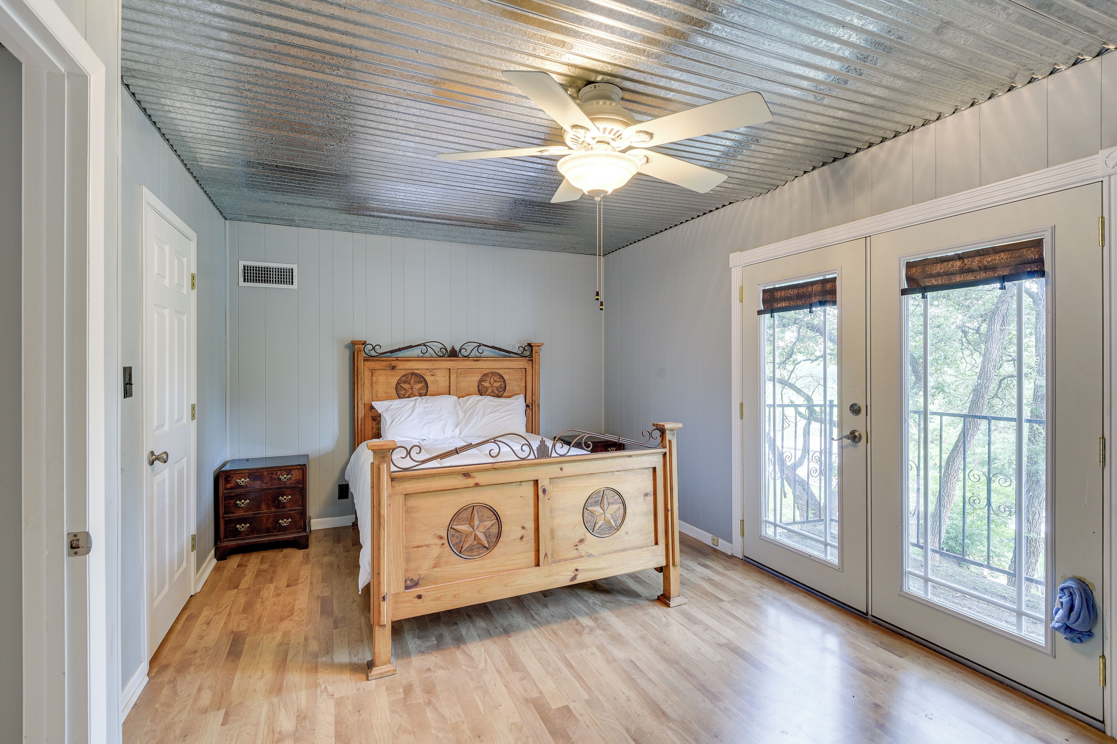 A bedroom with a wooden bed, a ceiling fan, and two windows with blinds.
