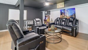 A modern living room with leather sofas, a massage chair, a gaming console, and a cityscape painting. - 'A Time to Remember' Home in Tobyhanna w/ hot tub (Tobyhanna)