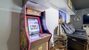 A retro arcade machine with a 40th anniversary plaque, a black leather couch, and a wall-mounted TV in a modern living room. - 'A Time to Remember' Home in Tobyhanna w/ hot tub (Tobyhanna)