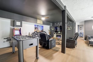 A modern living room with a foosball table, reclining chairs, a fireplace, and a wall-mounted TV. - 'A Time to Remember' Home in Tobyhanna w/ hot tub (Tobyhanna)