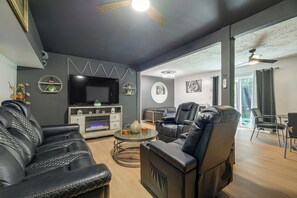 Un salon moderne doté d’un téléviseur à écran plat, de canapés en cuir, d’une cheminée et d’un coin repas avec une table et des chaises.