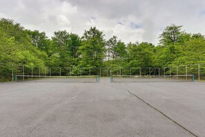 Una cancha de tenis al aire libre rodeada de árboles.
