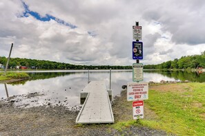 Un lago con un muelle y varios letreros, incluyendo advertencias sobre la pesca y el nado.