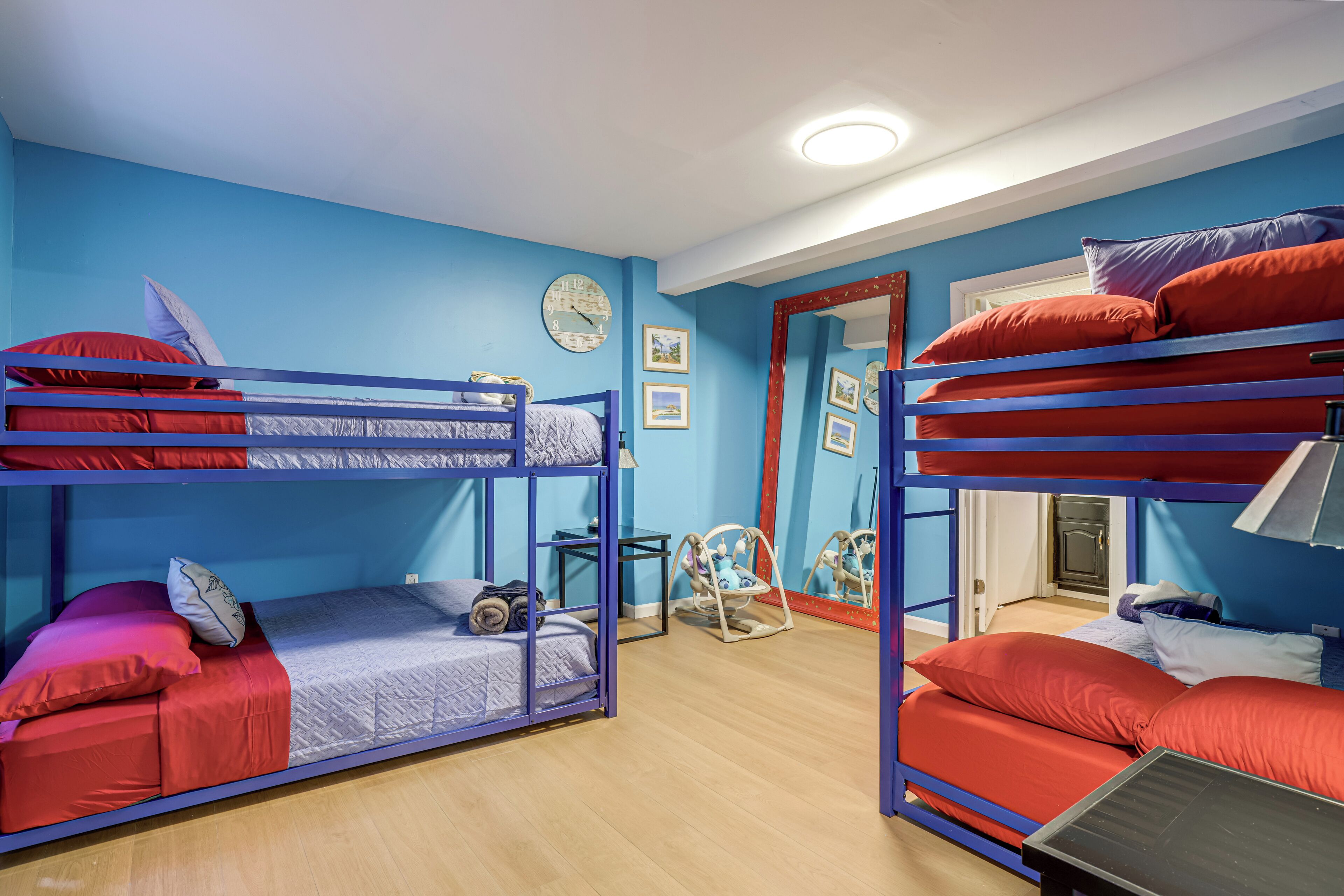 Une pièce avec des lits superposés, une petite table, un miroir et une horloge au mur.