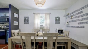 A dining area with a wooden table and chairs, a chandelier, and a kitchen in the background. - 'A Time to Remember' Home in Tobyhanna w/ hot tub (Tobyhanna)