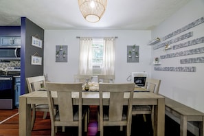 Un comedor con una mesa y sillas de madera, un candelabro y una cocina al fondo.