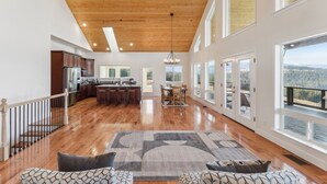 A spacious living area with a wooden ceiling, large windows, and a view of the outdoors.