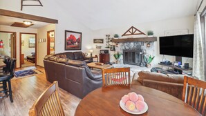 Un salon avec une cheminée, un téléviseur et un coin repas comprenant une table et des chaises.