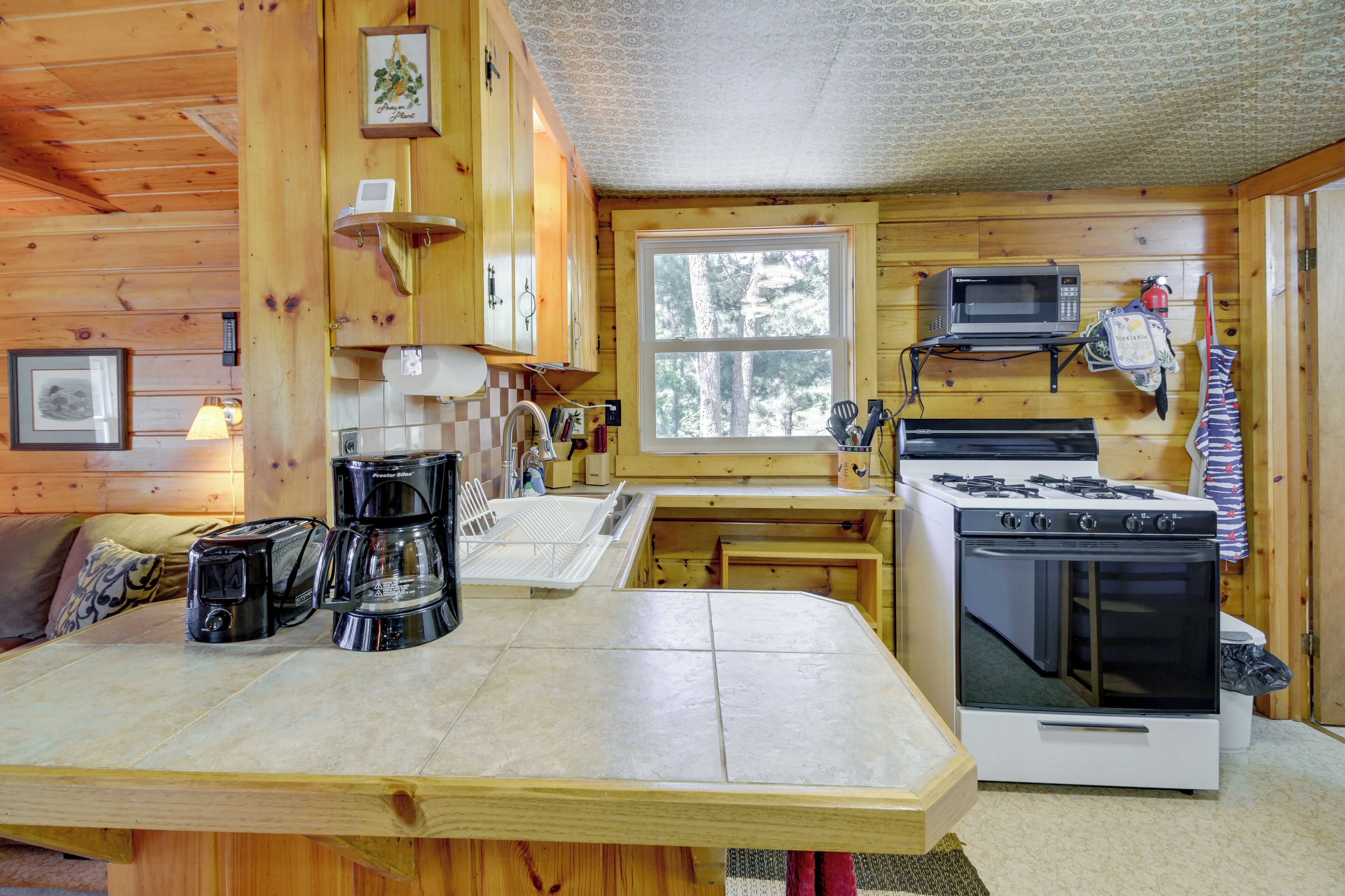 A wooden cabin kitchen with a stove, microwave, and coffee maker.