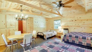A wooden cabin room with a bed, a table with chairs, a chandelier, and a ceiling fan. - Waterfront Pequot Lakes Cabin: Fire Pit + Views! (Pequot Lakes)