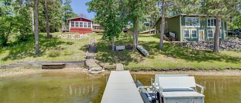 A dock extending into a body of water with a house in the background.