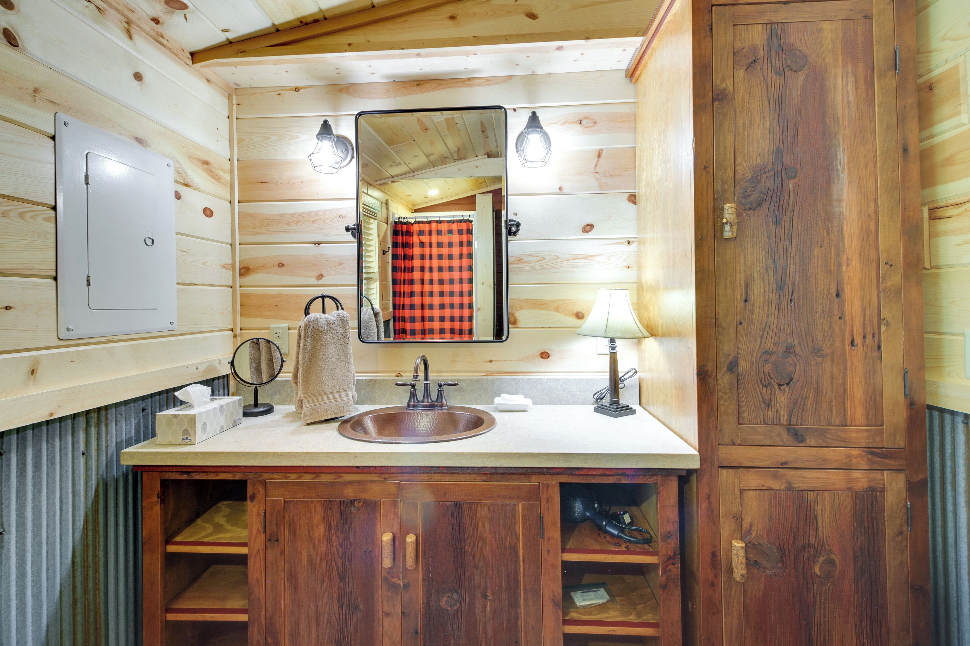 Une salle de bain rustique, aménagée dans une cabane en bois, avec un lavabo, un miroir, une serviette et un meuble de rangement.