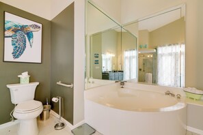 Een moderne badkamer met een groot bad, een toilet en een spiegel.