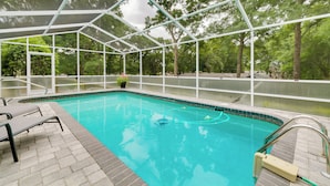 An indoor swimming pool with a glass enclosure, surrounded by a brick deck and equipped with lounge chairs. - Lanai & Grill: Sunny Home Near Rainbow Springs! (Dunnellon)