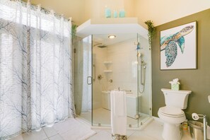 Een moderne badkamer met een glazen douchecabine, een wit toilet en een kunstwerk met daarop een zeeschildpad aan de muur.