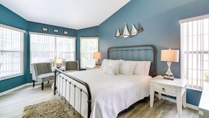 A bedroom with a bed, two nightstands, a chair, and a ceiling fan. - Lanai & Grill: Sunny Home Near Rainbow Springs! (Dunnellon)