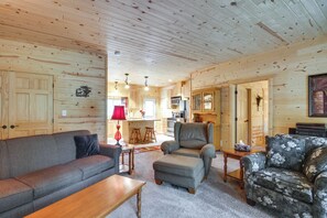 A cozy cabin interior with a living room, a kitchen, and a dining area.