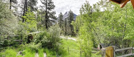 A forested area with a wooden structure, a wooden gate, and a mountain in the background.