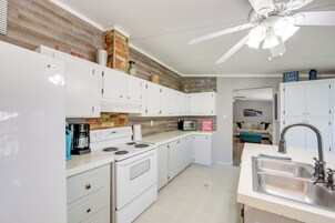 Una cocina moderna con armarios blancos, horno empotrado, microondas y pileta de acero inoxidable.