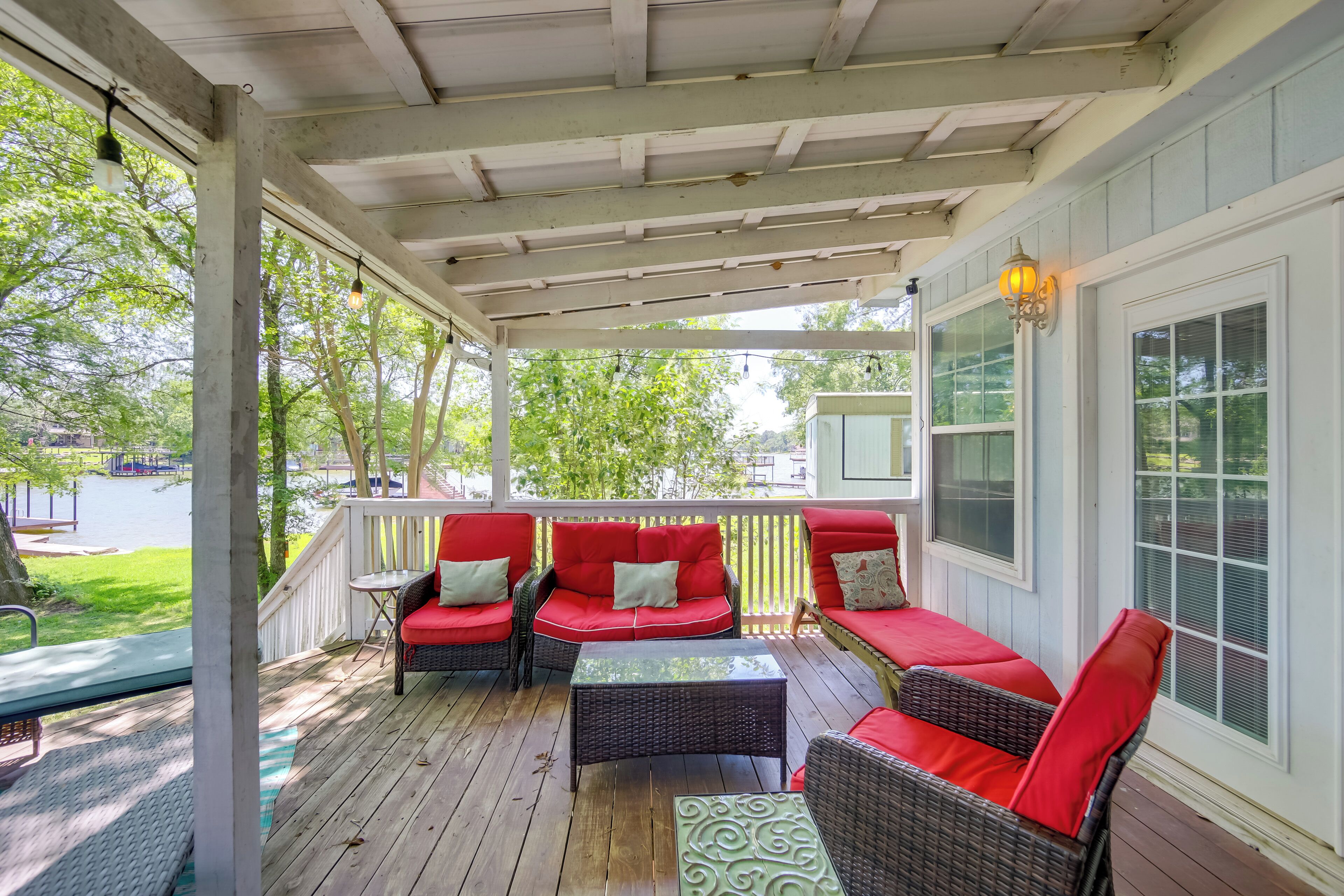 A covered porch with wicker furniture and a view of a lake.