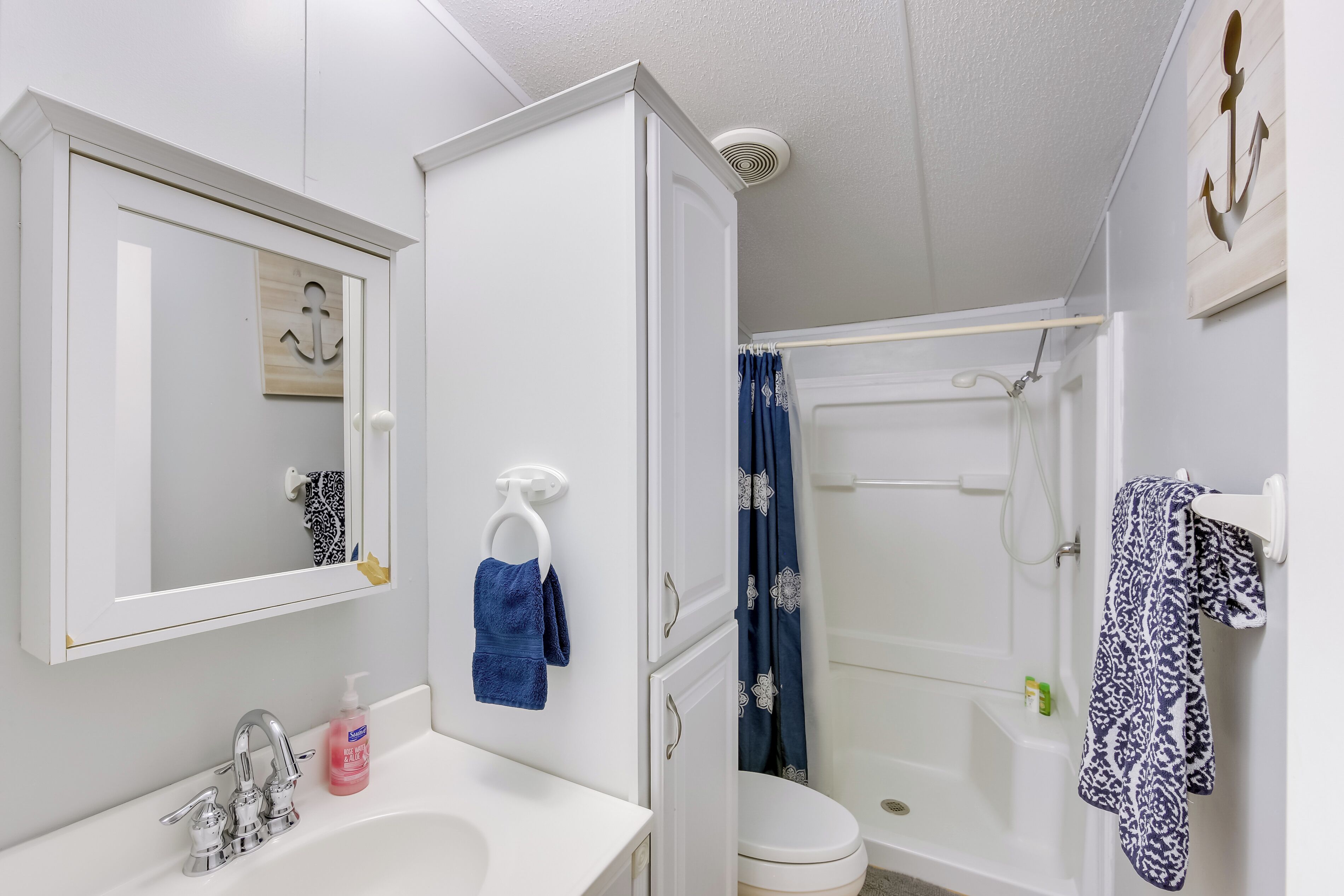 A bathroom with a white sink, mirror, and toilet. There is a shower curtain and a towel rack with towels.