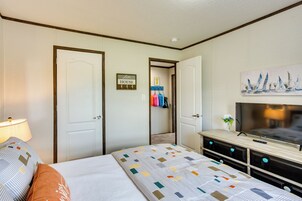 Una habitación de hotel con cama, televisor, cómoda y puerta que da a un pasillo.