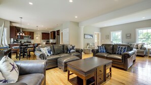 A spacious living room with leather sofas, a wooden coffee table, and a kitchen in the background. - Spacious Connecticut Home - Deck, Grill & Fire Pit (Mystic)