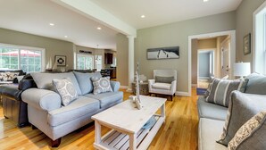 A spacious living room with a grey sofa, a white coffee table, and a grey armchair. - Spacious Connecticut Home - Deck, Grill & Fire Pit (Mystic)