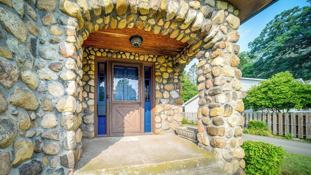 A stone house with a wooden porch and a blue door. - Central Erie Vacation Rental ~ 2 Mi to Beach! (Erie)