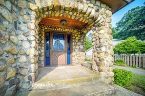 A stone house with a wooden porch and a blue door. - Central Erie Vacation Rental ~ 2 Mi to Beach! (Erie)