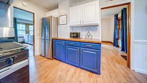 A modern kitchen with wooden flooring, white cabinets, and stainless steel appliances. - Central Erie Vacation Rental ~ 2 Mi to Beach! (Erie)