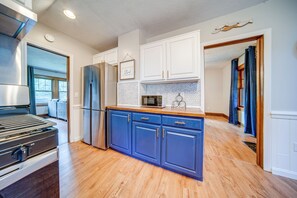 A modern kitchen with wooden flooring, white cabinets, and stainless steel appliances. - Central Erie Vacation Rental ~ 2 Mi to Beach! (Erie)