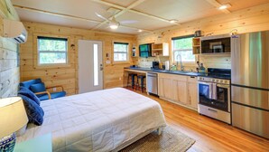 Una habitación tipo cabaña, compacta, con cama, kitchenette y ventilador de techo.