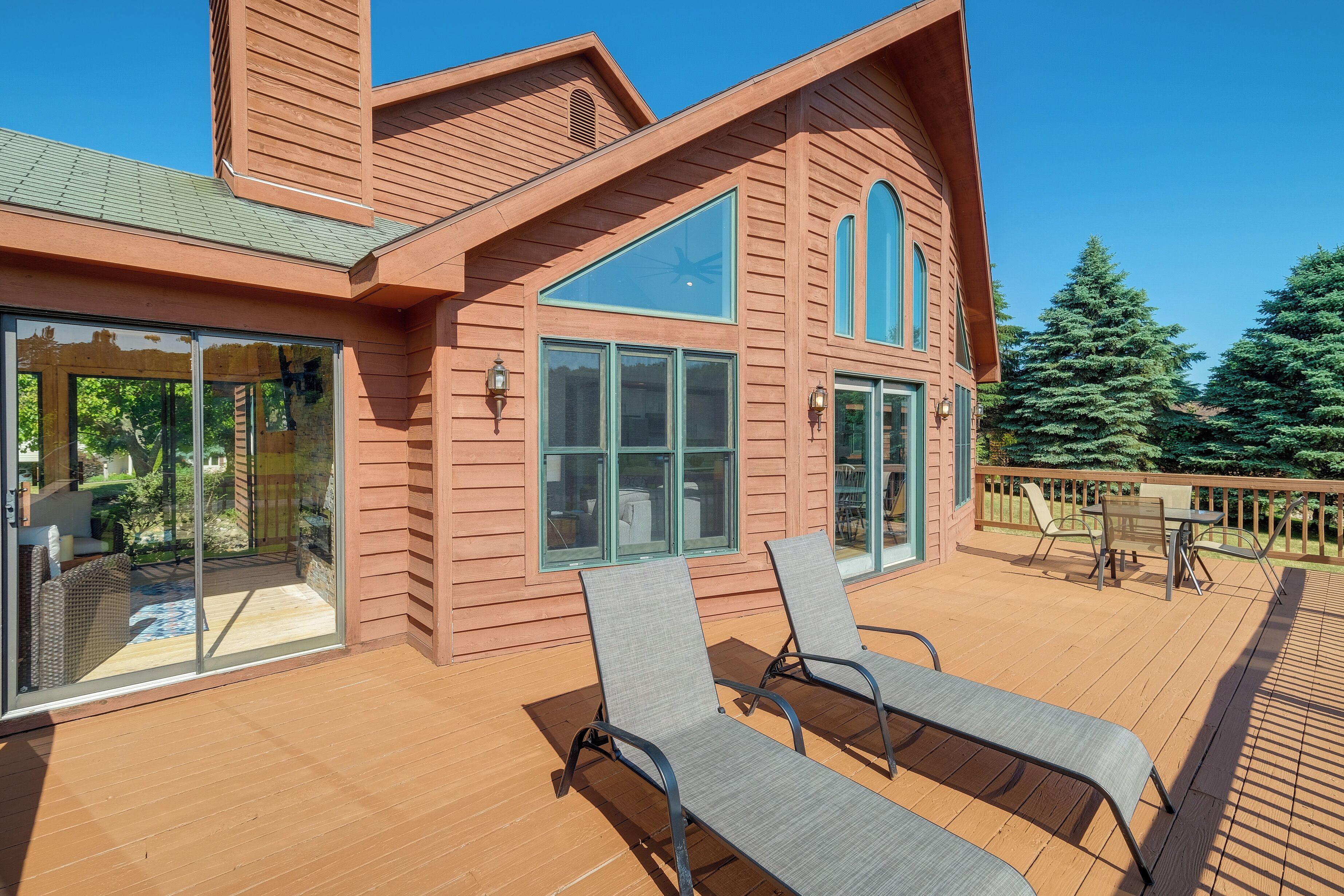 A modern wooden house with large windows and a deck.