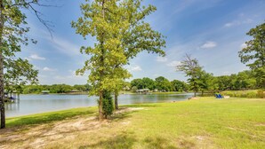 A lakeside park with a grassy area, a tree, and a distant view of a lake. - On Cedar Creek Reservoir: Malakoff Home w/ Pool! (Malakoff)
