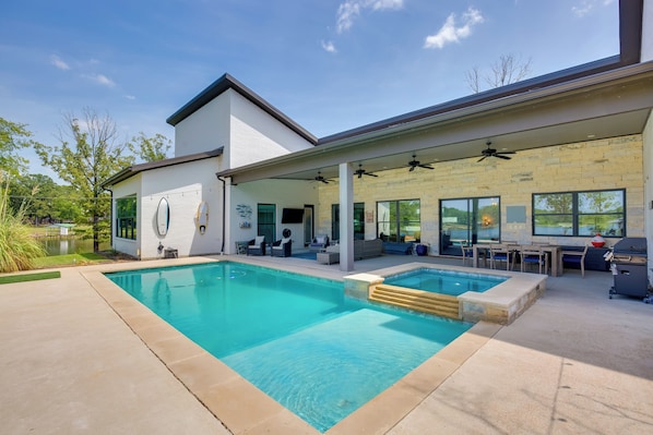 Uma casa moderna com uma piscina grande, área de estar ao ar livre e um alpendre coberto.