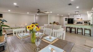A modern living room with a dining table set for four, a kitchen in the background, and a ceiling fan. - Arkansas Vacation Rental on Greers Ferry Lake! (Higden)