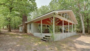 A rustic cabin with a covered porch, surrounded by trees. - Arkansas Vacation Rental on Greers Ferry Lake! (Higden)
